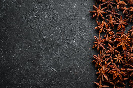 Fresh organic asian anise stars on black stone background. Badian - Indian spices. Top view.