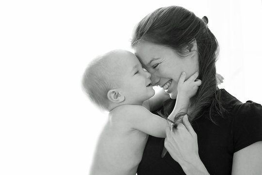 Black And White Side Portrait Of Young Woman Holding Little Baby. Child And Mother Laughing. Love And Tenderness