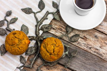 Fresh banana muffins and cup of coffee espresso on wooden table with wrought iron elements. Top view. Morning breakfast concept