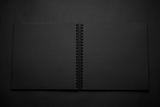 Blank black notebook on a black table, mockup photo. Blank black cover template with copy space for design. Black on black, minimal design concept.