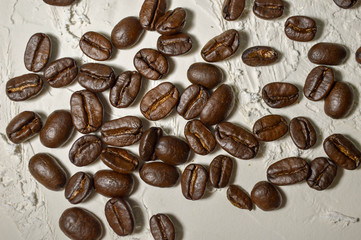 Close up shot of scattered coffee beans on a white surface. 