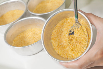 Closeup of spoon smashed crispy cracker in mould pan to make base of blueberry cheesecake. Process of cooking food. Homemade bakery. Selective focus.