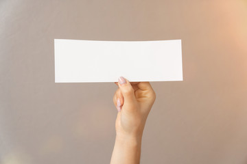 Fototapeta premium closeup on a light background a womans hand holds white paper for text inscription