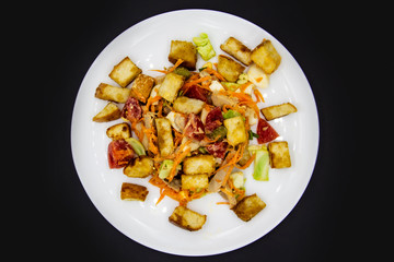 Salad with meat of pig, tomatoes, carrots, cabbage and crackers with bread runner with sauce on the white plate. Healthy and tasty meal for the diet. Delicious breakfast or lunch without GMO