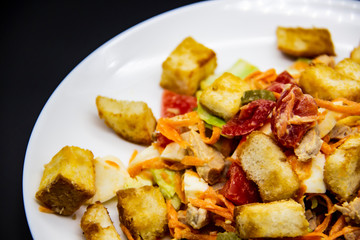 Salad with meat of pig, tomatoes, carrots, cabbage and crackers with bread runner with sauce on the white plate. Healthy and tasty meal for the diet. Delicious breakfast or lunch without GMO