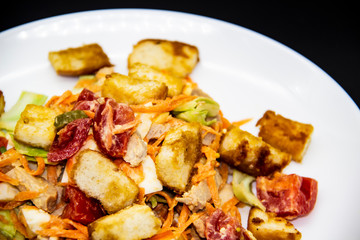 Salad with meat of pig, tomatoes, carrots, cabbage and crackers with bread runner with sauce on the white plate. Healthy and tasty meal for the diet. Delicious breakfast or lunch without GMO