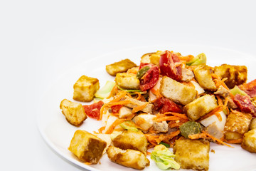 Salad with meat of pig, tomatoes, carrots, cabbage and crackers with bread runner with sauce on the white plate. Healthy and tasty meal for the diet. Delicious breakfast or lunch without GMO