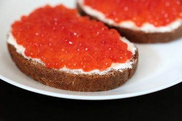 Sandwiches with red caviar and butter on white plate. Traditional russian dish