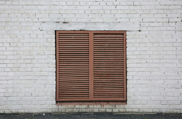 Barred ventilation window in white brick wall