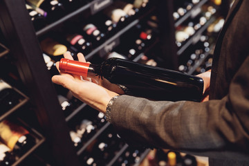Bartender sommelier takes bottle of red wine from counter of restaurant drinks store
