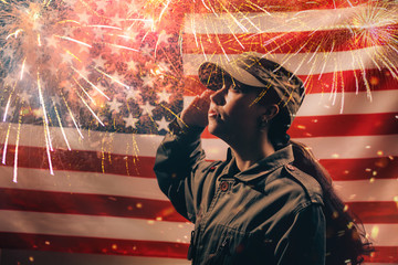 Memorial day. A female soldier in uniform salutes against the background of the American flag with...
