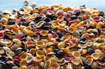 pasta made of durum wheat of different colors and shades, raw sprinkled on a table