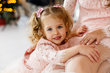 Portrait of little girl lying on mother's knees. Happy family having fun together at home. Family relationship concept. Stay home. Isolation together. Cozy home. Parents spending time with kid at home