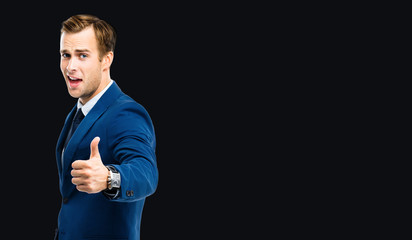 Excited businessman showing thumbs up like hand sign gesture, in blue confident suit, standing over...