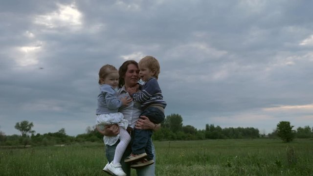 Happy Mother Holding Son and Daughter on Hands in the Field. Slow motion