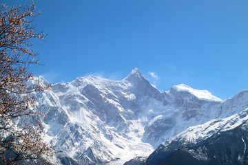 Through the mountains and wild pink peach blossoms, looking at Nanjiabawa Peak, against the blue sky, white clouds, and green water, it is even more steep and majestic!