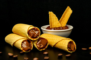 Wafer rolls with condensed milk on a white plate.