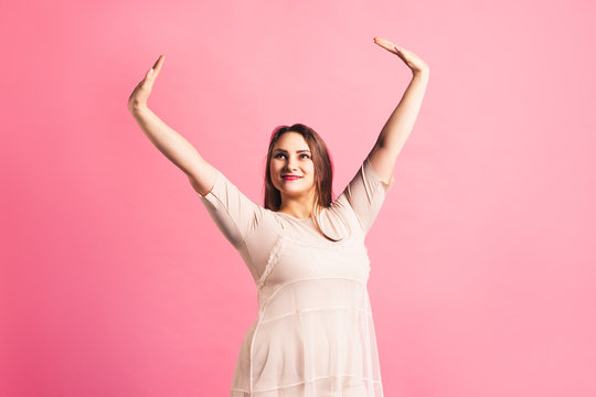 Plus size fashion model in beige dress, fat woman on pink background