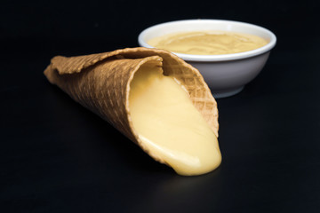 Wafer rolls with condensed milk on a white plate.