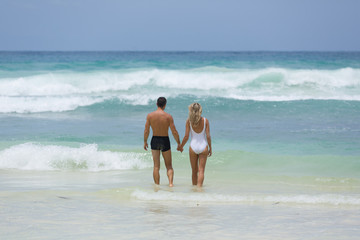 Lover couple enjoy their vacation at tropical beach together in the blue water of the Indian Ocean, in Seychelles.