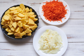 raw carrots grated, chopped onions, potatoes. Preparing to cook baked potatoes with vegetables.