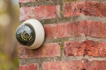 Fake security camera on the wall outside. security camera on a brick pillar in the yard.