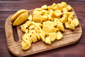 peeled sliced raw potatoes on a wooden board. Preparing vegetables for cooking.