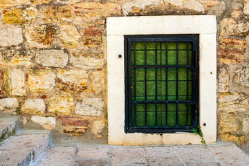 Fototapeta na wymiar Authentic, stone wall, with beautiful green, old, wooden shutters and window, background.