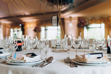 Beautiful table setting with crockery and flowers for a party, wedding reception or other festive event. Glassware and cutlery for catered event dinner.