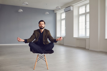 Calm meditative bearded businessman relaxes sitting on a chair in the office.