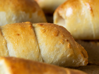 Close-up of sausages baked in dough on a baking sheet. Side view