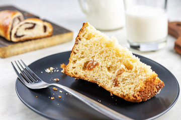 Pie with poppy seeds sliced into pieces, on wooden boards and in a dish, a glass and a jug with milk, selective focus, shallow depth of field, light background, top lighting.