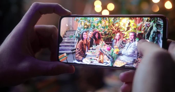 Close up man taking picture with smartphone of friends meal