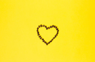 Heart of coffee beans on yellow background. Flat lay. Creative Minimal food concept. Copy space