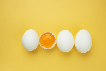 Top view, fresh chicken eggs isolated on a yellow background. Natural healthy food and organic nutrition concept.