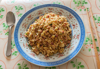A plate of fried rice with ham and mushroom served on a table in a restaurant