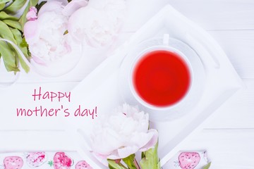 Happy mother's day greeting card. Pink fruit tea and flowers peonies on white wooden background