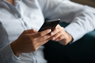 Close up focus on smartphone in female hands. Young mixed race woman using mobile applications,...