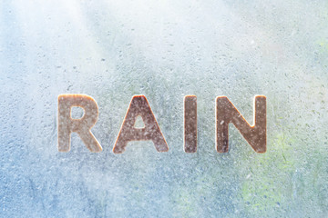 Inscription rain on wet glass in the rain. Spring, sunny rain. Be happy