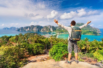 Travel man with photo backpack enjoy amazing view nature landscape island phi-phi from top of mountain at sunrise. Active lifestyle and Travel concept