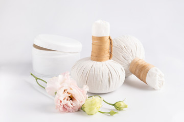Fototapeta na wymiar Cosmetic set for massage with bags of herbs, jar of cream and flower.