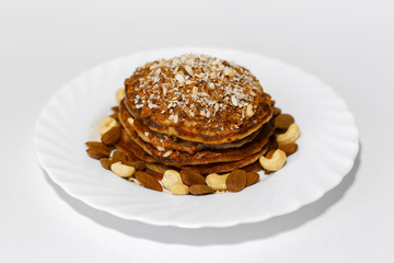 Healthy breakfast, homemade american vegan pancakes with raw cashew and almond nuts in white plate.