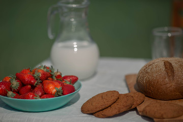Still life withStill life with bread and milk, strawberries and oatmeal cookies on a table .