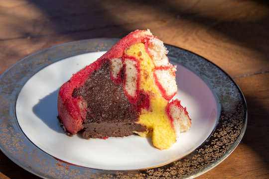 Close up of a slice of beautiful italian dessert, the Zuppa Inglese dessert, a trifle cake with chocolate and vanilla cream fillings and red Alchermesspirit.