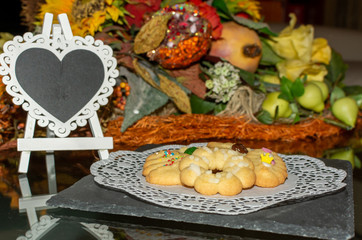 Cookies with an Hart Shaped Empty Blackboard on Flowered Background. Concept for love celebrations...
