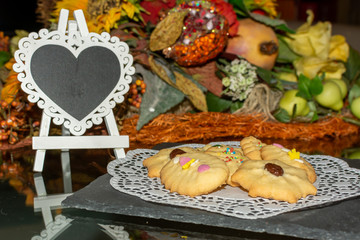 Cookies with an Hart Shaped Empty Blackboard on Flowered Background. Concept for love celebrations and party