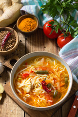 Tukpa soup of Indian cuisine. Hot noodle soup with chicken, ginger, cilantro and spices on a deyven wooden table.