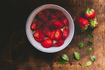 Sliced strawberries in the bowl on a rustic wooden table