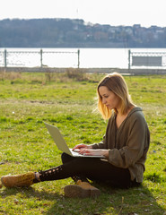 Young girl with laptop computer sitting on the grass images