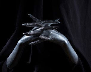 two beautiful man's hands in silver paint on a black background